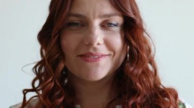 Güzel kıvırcık saçlı beyaz kız kameraya bakıyor ve gülümsüyor.