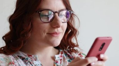 Kafkasyalı güzel bir kadın akıllı telefon kullanıyor, evde kulaklıkla dinleniyor. İyi titreşimler..