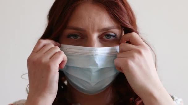 Schöne junge Mädchen zieht ihre medizinische Schutzmaske aus ihrem Gesicht zu Hause — Stockvideo