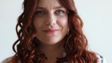 Beyaz kadın kameraya gülümsüyor. Kıvırcık saçlar