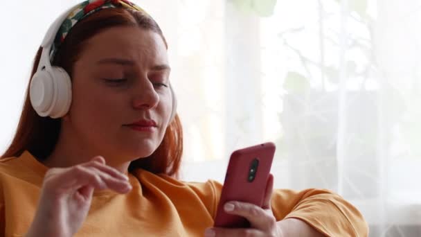 Hermosa mujer caucásica escuchando música con auriculares en casa. — Vídeos de Stock