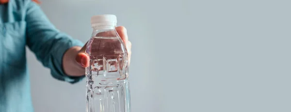 Vrouw Met Een Fles Water Tegen Een Grijze Achtergrond — Stockfoto