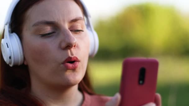 Chica alegre positiva escuchando música usando el teléfono móvil — Vídeo de stock