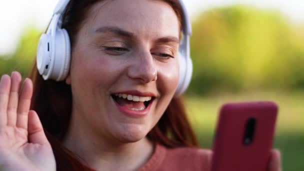 Chica feliz estudiante usando teléfono inteligente videoconferencia llamando a distancia social al aire libre. — Vídeos de Stock