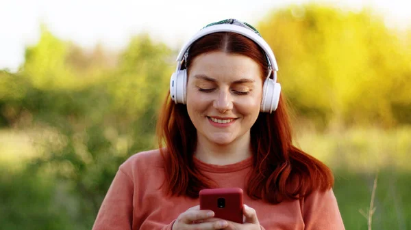 Jeune femme écoutant de la musique avec smartphone le jour ensoleillé — Photo