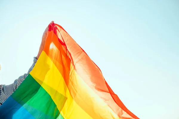 Jovem mão com uma bandeira de orgulho colorido arco-íris lgbt — Fotografia de Stock