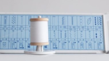 Spool with white thin thread on working a new sewing machine. Spool with thin white thread on working sewing machine.