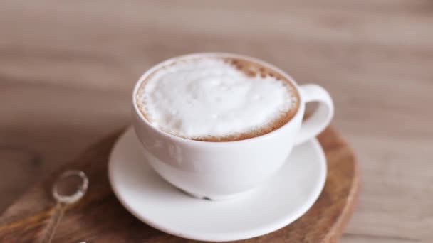 Cappuccino kávé kerámia csészében, fa táblán. Otthon kávét főzök. Finom reggeli. — Stock videók