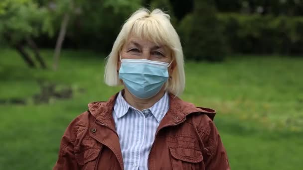 Influensavirus sprider skyddsmask som skyddar mot influensavirus och sjukdomar. Kaukasisk 50-årig kvinna med kirurgmask i ansiktet på offentliga platser. Hälso- och sjukvård. — Stockvideo