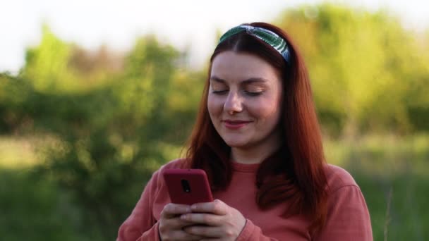 Portrait de jeune femme millénaire souriant visage élégant en utilisant smartphone à l'extérieur sur la rue à l'extérieur. Communication en ligne — Video