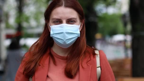 Young caucasian millennial girl in a protective mask in a city park. Flu disease virus spreading protection mask protective against influenza viruses and diseases. — Vídeo de Stock