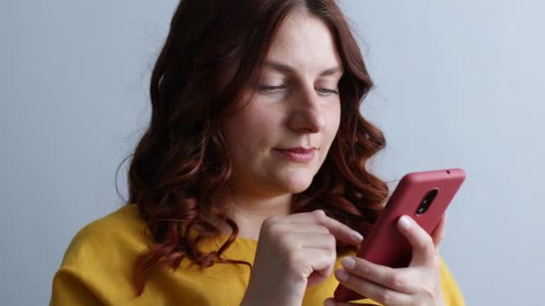 Junges Mädchen hält Handy in der Hand, chattet in sozialen Netzwerken im Wohnzimmer. — Stockvideo