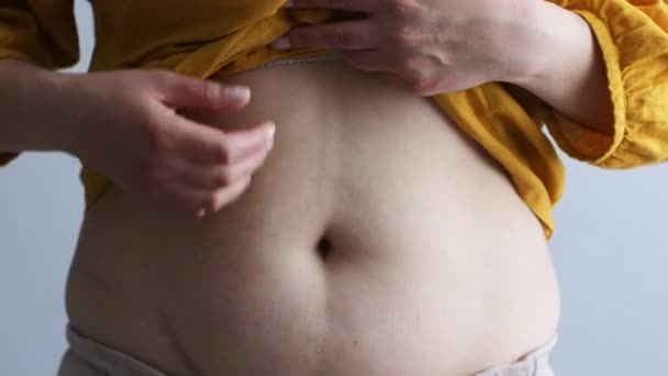 Υπερβολικό βάρος συν μέγεθος γυναίκα αγγίζει το λίπος κοιλιά της σε γκρι φόντο — Αρχείο Βίντεο