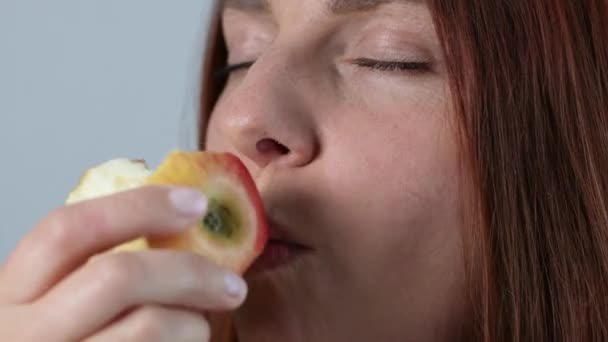 Retrato de una hermosa joven caucásica mordiendo manzana roja madura. Cara femenina comiendo manzana. Fruta en verano. — Vídeos de Stock