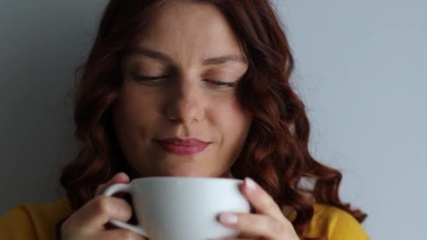 Glückliche hübsche Frau hält Becher in der Hand und genießt Kaffee zu Hause — Stockvideo