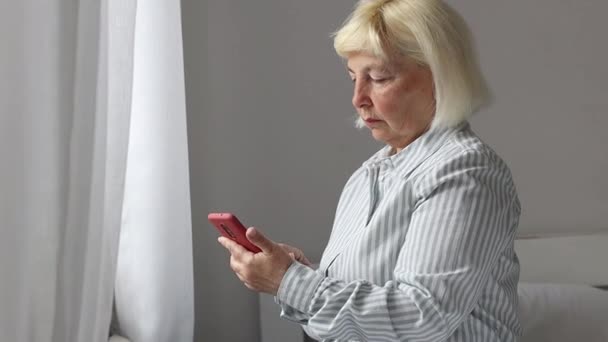 Senora 50 Jahre alte Frau SMS auf Mobiltelefon mit Wifi-Internet zu Hause hält Handy. — Stockvideo