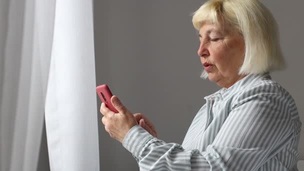 Kaukasische 50 Jahre alte Frau, die per Mobiltelefon SMS mit Wifi-Internet zu Hause hält Handy. 5G-Technologie. — Stockvideo