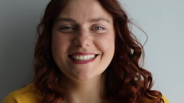 Νεαρή γυναίκα γελάει από ένα αστείο σε γκρι φόντο — Αρχείο Βίντεο