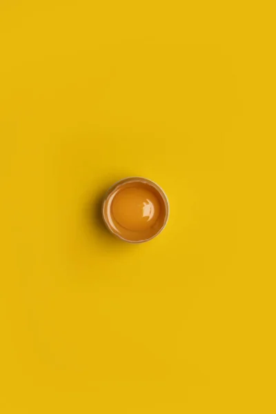 Minimal Easter concept idea. Fresh Easter one brown chicken broken egg with yolk on yellow background. — Foto de Stock