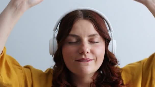 Donna millenaria positiva che ascolta musica su cuffie che cantano, godendo l'audio a casa all'interno. Teenager ballare divertimento alla musica — Video Stock