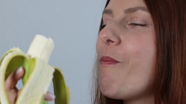 Gros plan de charmante femme caucasienne joyeuse mordant banane mûre jaune et regardant dans la caméra. Visage manger de la banane — Video