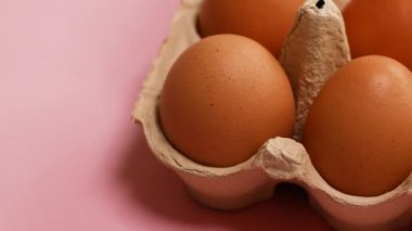 Sepette yumurtalar. Pembe arka planda organik kahverengi yumurtaları olan yumurta kutusunu aç.