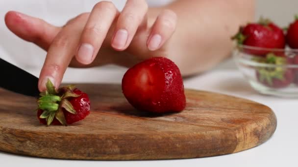 La hembra corta la fresa madura en una tabla de madera en la cocina. Concepto de comida saludable — Vídeos de Stock