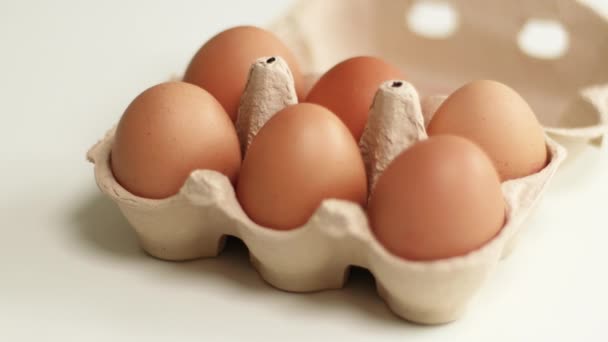Uova nel cestino. Un vassoio di uova di galline fresche marroni su sfondo bianco. Uova di pollo biologiche — Video Stock