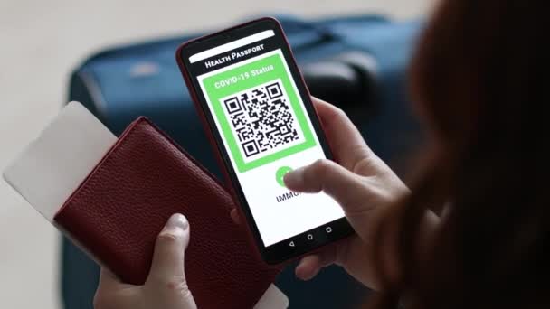 Mulher mão turista usando aplicativo passaporte imunidade no telefone móvel para viagens. Mulher viajante à espera de embarque — Vídeo de Stock