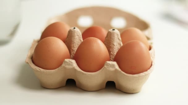 Organic chicken eggs in a brown paper box placed on white table. Eggs provide protein — Stock Video