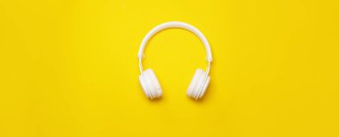 Sarı arka planda kablosuz kulaklık ve fotokopi alanı. Müzik ve moda konsepti. Moda asgari biçimi.