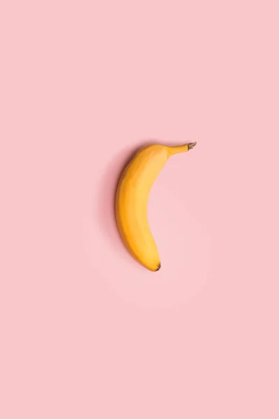 Жовтий стиглий банан на рожевому тлі. Мінімальна художня композиція — стокове фото