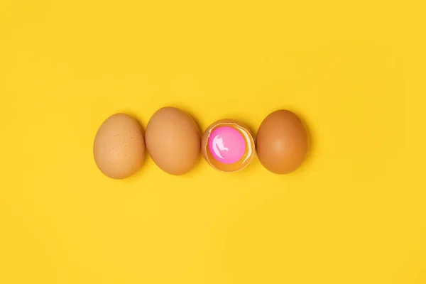 Lekkere bruine kippeneieren en een gebroken ei met dooier op gele achtergrond — Stockfoto