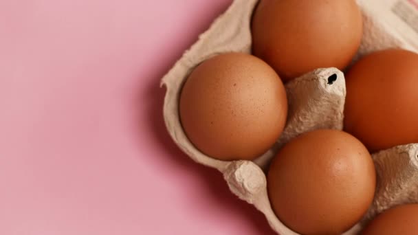 알을 바구니에 담는다. 분홍색 배경에 갈색 달걀이 들어 있는 계란 상자를 열어 보 세요. 건강 한 음식 과 유기농 단백질 아침 식사 개념 — 비디오