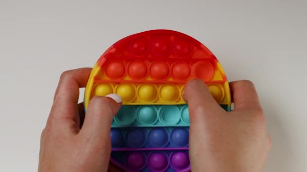 Childs hand presst auf pop it Spielzeug Silikon auf einem grauen Hintergrund — Stockvideo