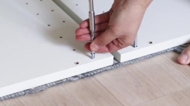 Man assembling furniture. Assembly furniture using screwdriver at home