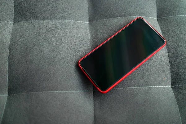 Modern smartphone gadget with black blank screen on sofa —  Fotos de Stock