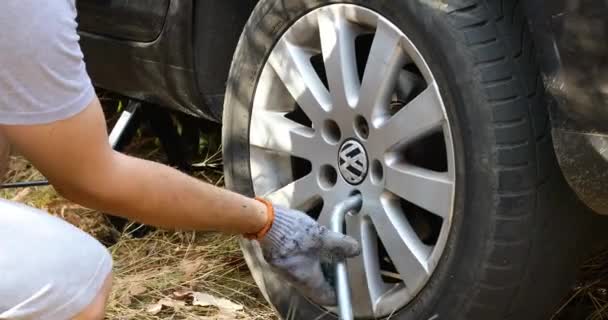 Podolsk, Ukraine: October 25, 2020 Traveler Man changing flat tire on the road. Replacing broken vehicle tire on the grass — Vídeos de Stock