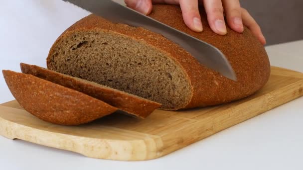 Close-up of woman cutting whole grain bread in the kitchen. — Video Stock
