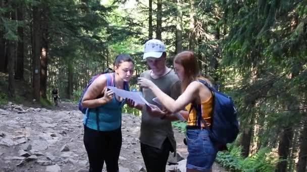 Two women and one men searching direction on location map while traveling. Travel, hiking and active lifestyle concept — Stock video