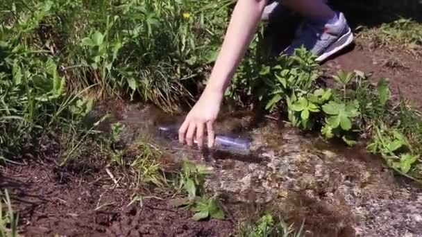 Woman hand collects clean spring water from spring in transparent plastic bottle — Video