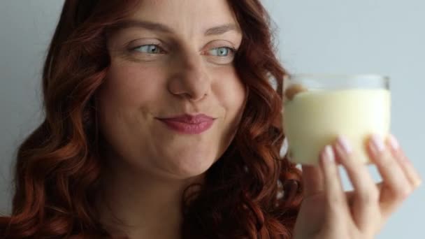 Gadis kulit putih berambut keriting yang positif makan makanan penutup yang lezat, menikmati rasa pada latar belakang abu-abu — Stok Video