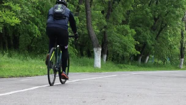 Mężczyzna w sportowej odzieży jeździ ścieżką rowerową w miejskim letnim parku — Wideo stockowe