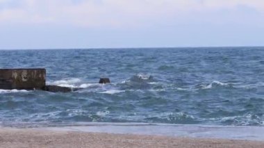 Waves beat against a concrete pier. Lots of splashes. Sea. Waves.