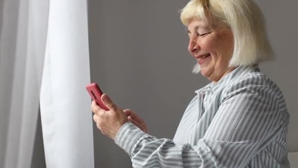 Blanke knappe oudere vrouw sms 't op mobiele telefoon met behulp van wifi internet thuis met mobiele telefoon. 5G-technologie apparaat. — Stockvideo