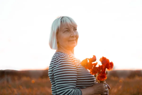 Glad blond hår kvinna dam håller röda vallmo bukett på fältet vid solnedgången — Stockfoto