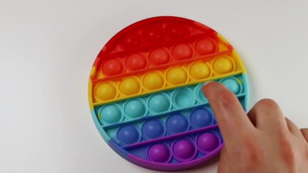 Rainbow sensoriska fidget isolerad i handen på vit bakgrund. Antistress pop det leksak. — Stockvideo