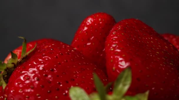 Свіжі органічні червоні стиглі полуничні фрукти на темному фоні, крупним планом. Збирання ягід . — стокове відео