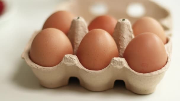 Barna bio csirke tojás barna papírtálcán, fehér asztalra helyezve. Környezetbarát tojástermelés. — Stock videók