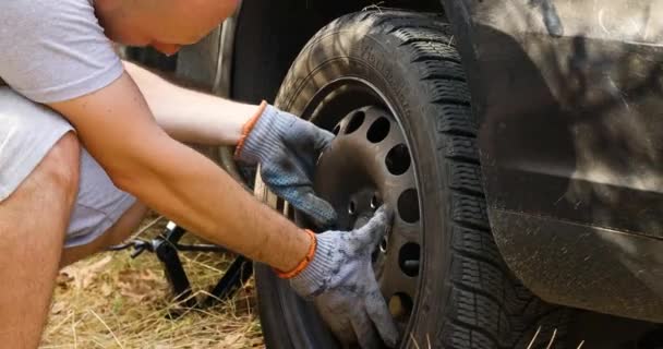 Llanta pinchada en la carretera. Hombre viajero cambiando neumáticos en el coche en el lado de la carretera — Vídeos de Stock